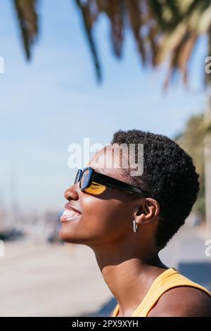 Vertikales Porträt von einer Seite einer afrikanerin mit sehr kurzen Haaren, die wegschauen Stockfoto