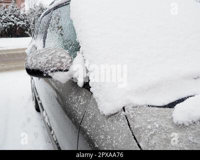 Schnee und Eis auf der Windschutzscheibe, den Rückspiegeln des Fahrzeugs. Winterliche Fahrbedingungen. Schneeräumen. Strassenverkehr im Winter. Metall Stockfoto