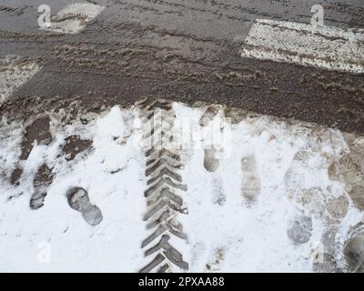 Eine Gabel oder ein Schild aus einem Kreisverkehr. Schneeverwehungen am Straßenrand. Schlechtes Verkehrswetter. Fußspuren im Schnee. Schwierige Fahrbedingungen. Gewinnen Stockfoto