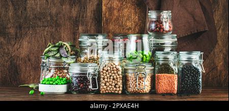 Getrocknete, rohe und frische Hülsenfrüchte und Bohnen in Glasgefäßen. Linsen, Kichererbsen, Mungbohnen, Sojabohnen. Gesunde Lebensmittel, vegane Proteine, Mikronährstoffe und Ballaststoffe Stockfoto