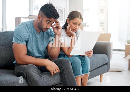 Was machen wir jetzt? Ein junges Paar, das zu Hause auf dem Sofa sitzt und sich gestresst fühlt, nachdem es einen Räumungsbescheid erhalten hat. Stockfoto