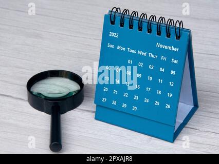 Juli 2022 blauer Tischkalender auf Holzschreibtisch mit Kopierraum und Lupe Stockfoto