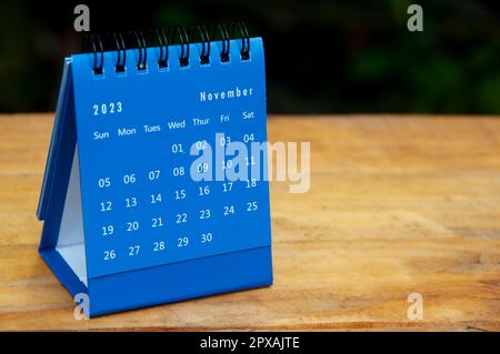 Blauer Tischkalender für November 2023 auf Holztisch mit anpassbarem Platz für Text. Stockfoto