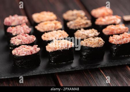 Set aus Gunkan Maki Sushi mit verschiedenen Arten von Fischlachs, Jakobsmuscheln, Barsch, Aal, Garnelen und Kaviar auf Holztisch-Hintergrund. Sushi-Menü. Japanisch Stockfoto