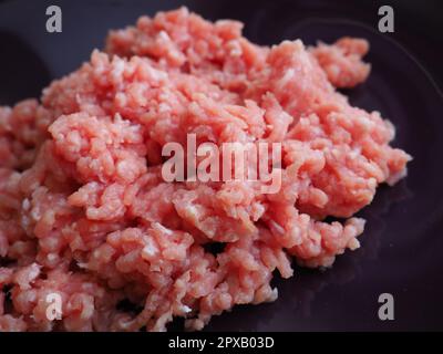 Hackfleisch auf einem großen lila Keramikteller. Köstliches frisches Hackfleisch für die Zubereitung von Koteletts, Steaks, Hamburgern und Fleischbällchen. Halbfertigerzeugnis aus Schweinefleisch Stockfoto