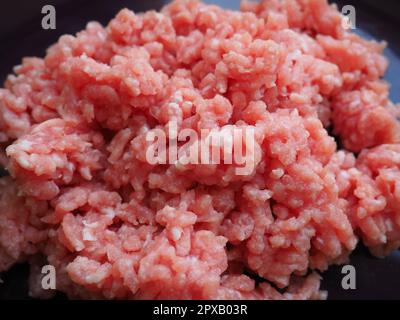Hackfleisch auf einem großen lila Keramikteller. Köstliches frisches Hackfleisch für die Zubereitung von Koteletts, Steaks, Hamburgern und Fleischbällchen. Halbfertigerzeugnis aus Schweinefleisch Stockfoto