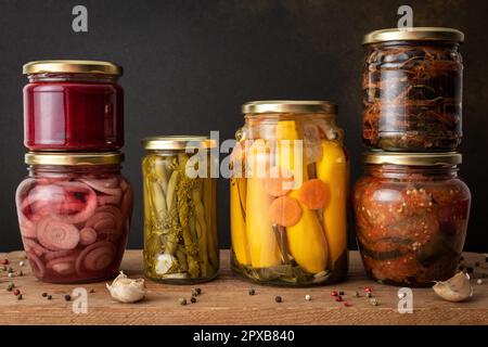 Gemüse für den Winter konservieren, Gemüse in Dosen auf einem Holztisch gegen eine braune Wand, eingelegtes oder fermentiertes Gemüse, Platz kopieren Stockfoto