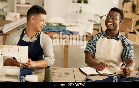 Zwei Schneider, die reden und lachen. Fröhliche Geschäftsleute, die zusammenarbeiten und reden. Zwei Designkollegen planen ihre Strategie. Vielfältige Kollegen Stockfoto