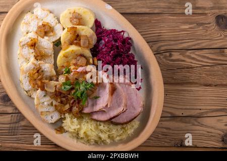 Geräuchertes Fleisch, serviert mit Rot- und Weißkohl und zwei Sorten Knödel Stockfoto