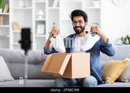 Video Wird Ausgepackt. Der Hübsche Indianer Packt Sein Paket Mit Neuen Schuhen Aus Stockfoto