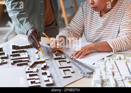 Nahaufnahme von Konstrukteuren, die im Team am Modell des Gebäudes arbeiten, sie zeichnen einen Entwurf und diskutieren Modelle Stockfoto