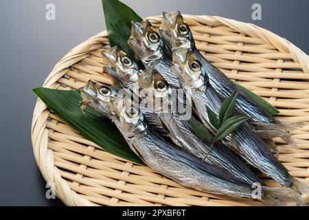 Ulmae-Sardinen in einem Sieb auf schwarzem Hintergrund serviert. Japanisches Essen, getrockneter Fisch. Stockfoto