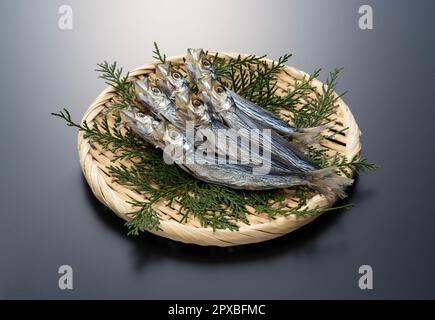 Ulmae-Sardinen in einem Sieb auf schwarzem Hintergrund serviert. Japanisches Essen, getrockneter Fisch. Stockfoto