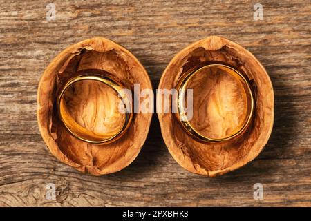 Öffnete Walnusshülle mit goldenen Eheringen. Liebe und Heiratskonzept. Stockfoto