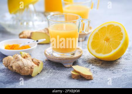 Hausgemachte Kurkuma Zitrone Ingwer Shots in kleinen Gläsern, gesunde Ingwer Zitrone Kurkuma Shot – ideal, um das Immunsystem im Winter zu stärken Stockfoto