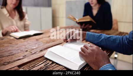 Junge, Multiethnische Menschen, Die Über Dem Holzschreibtisch Bibel Lesen Stockfoto