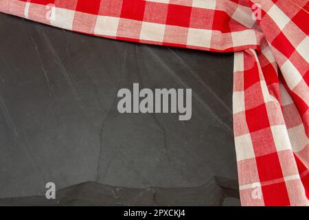Rotes weißes kariertes Tischtuch auf massivem Schieferteller oder schwarzer Steinhintergrund. Vorlage für Design-Menükarte und Tafel. Speicherplatz kopieren. Oben Stockfoto