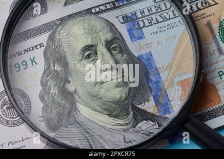 Ein Fragment von einem Hundert-Dollar-Schein mit einem Porträt von Benjamin Franklin unter einer Lupe Stockfoto