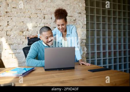 Zwei verschiedene Kollegen, die Videoanrufe auf einem Laptop in einem Büro zur Zusammenarbeit führen. Selbstbewusstes Team, das online virtuelle Konferenzen mit Partnern abhält Stockfoto