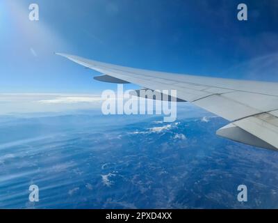 Blick von einem Flugzeug auf den Flügel und die Wolken darunter Stockfoto