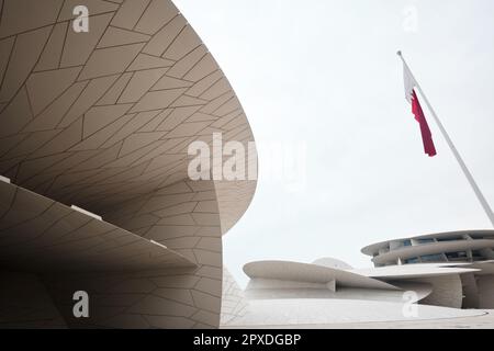 Doha, Katar - 2023. April: Das Nationalmuseum von Katar, entworfen vom Architekten Jean Nouvel, das Museum hat die Form einer Wüstenrose mit der katarischen Flagge Stockfoto