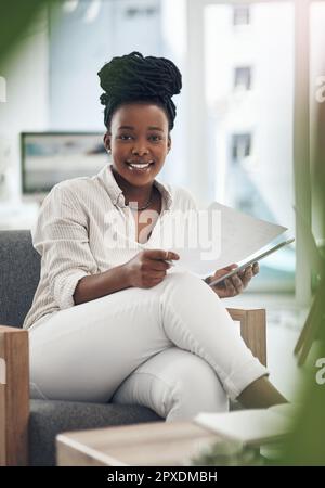 Das Geschäft boomt in letzter Zeit. Eine Geschäftsfrau, die ihr digitales Tablet verwendet, während sie Papierkram liest. Stockfoto