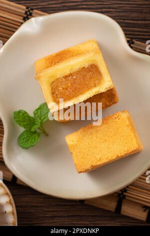 Köstliches taiwanesisches berühmtes Ananaskuchen Gebäck als Dessert auf einem Teller auf einem Holztisch mit heißem Tee. Stockfoto