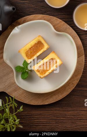 Köstliches taiwanesisches berühmtes Ananaskuchen Gebäck als Dessert auf einem Teller auf einem Holztisch mit heißem Tee. Stockfoto