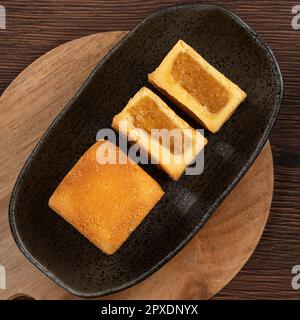 Köstliches taiwanesisches berühmtes Ananaskuchen Gebäck als Dessert auf einem Teller auf einem Holztisch mit heißem Tee. Stockfoto