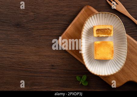 Köstliches taiwanesisches berühmtes Ananaskuchen Gebäck als Dessert auf einem Teller auf einem Holztisch mit heißem Tee. Stockfoto
