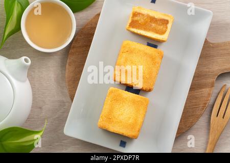 Köstliches taiwanesisches berühmtes Ananaskuchen Gebäck als Dessert auf einem Teller auf einem Holztisch mit heißem Tee. Stockfoto