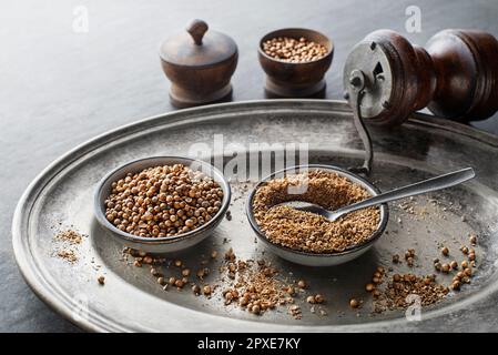 Organisch getrocknete Koriandersamen (Coriandrum sativum) und Pulver auf rustikalem Hintergrund. Gesunde Ernährung, indische Gewürze, Geschmack, Vitamin. Stockfoto