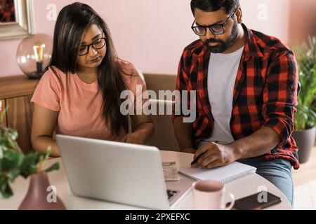 Ernsthafte Ehefrau und Ehemann planen Budget, prüfen Finanzen, fokussierte junge Frau mit Online-Rechner und Zählen von Rechnungen oder Steuern, Mann mit Laptop Stockfoto