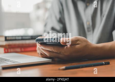 Mann mit Handy und Laptop im Büro. Freiberufler bei der Arbeit. Stockfoto