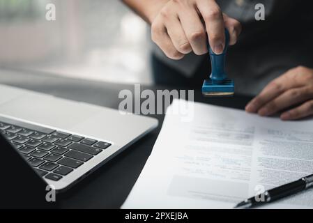 Mann, der die Genehmigung von Dokumenten für das Bankwesen oder das Investment-Marketing auf dem Schreibtisch stempelt. Stockfoto