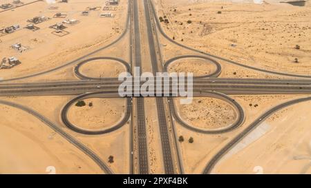 Luftaufnahme eines erhöhten Autobahnkreuzes in einer Wüstenlandschaft in Dubai, Vereinigte Arabische Emirate. Stockfoto