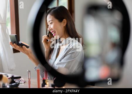 Kosmetikblogger mit Pinsel und Pulver zum Auftragen des Produkts zur Prüfung von Kosmetika im Make-up-Vlogger. Stockfoto
