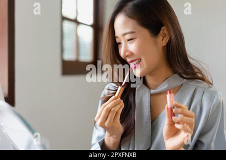 Schönheitsbloggerin, die Lippenstift auf ihren Mund aufträgt und Kosmetikprodukte im Make-up-Vlogger überprüft. Stockfoto