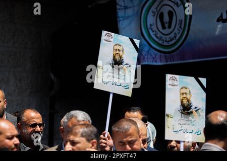 Gaza, Palästina. 02. Mai 2023. Die Menschen versammeln sich vor dem Gebäude des Internationalen Komitees vom Roten Kreuz (IKRK) in Gaza-Stadt, während sie das Poster des palästinensischen Gefangenen Khader Adnan halten, der nach einem 87-tägigen Hungerstreik in einem israelischen Gefängnis am 02. Mai 2023 starb. Khader Adnan trat als Reaktion auf seine administrative Inhaftierung 66 Tage im Jahr 2012, 52 Tage im Jahr 2015, 59 Tage im Jahr 2018 und 25 Tage im Jahr 2021 in den Hungerstreik. Foto: Ramez Habboub/ABACAPRESS.COM Kredit: Abaca Press/Alamy Live News Stockfoto