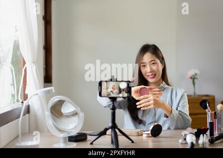 Schönheitsblogger hält Rouge und zeigt das Produkt, um Kosmetik im Make-up-Vlogger zu bewerten. Stockfoto