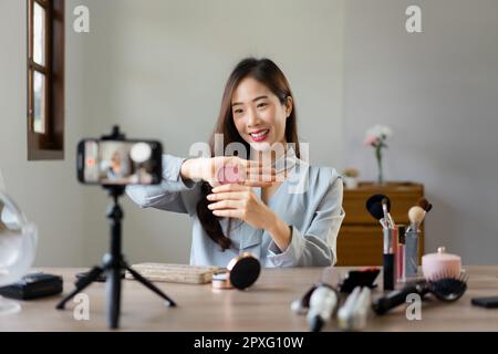Schönheitsblogger hält Rouge und zeigt das Produkt, um Kosmetik im Make-up-Vlogger zu bewerten. Stockfoto