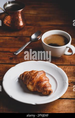 Croissant auf weißem Teller und Tasse türkischer Kaffee zum Frühstück Stockfoto