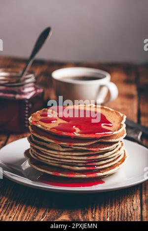 Stapel Pfannkuchen mit Beeren Marmelade auf weiße Platte über Holz- Tabelle Stockfoto
