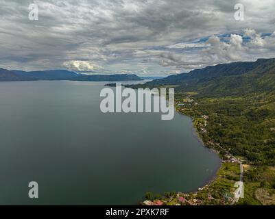 Lake Toba und die Insel Samosir mit Häusern am Ufer von oben. Sumatra, Indonesien. Stockfoto