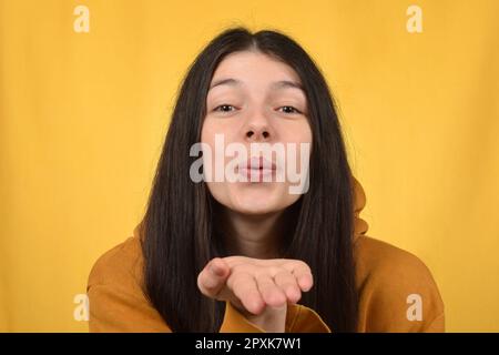 Süße, hübsche brünette Frau macht einen Luftkuss Stockfoto