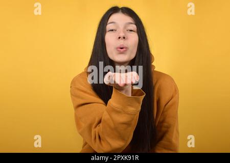 Süße, hübsche brünette Frau macht einen Luftkuss Stockfoto