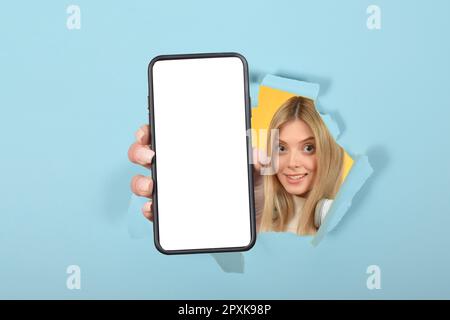 Ein positiver Millennials mit Smartphone und weißem, leerem Bildschirm auf farbenfrohem Studiohintergrund Stockfoto