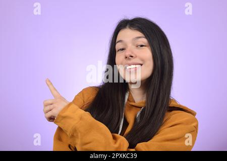 Junge, hübsche Frau, die mit dem Finger in die Richtung zeigt Stockfoto