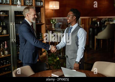 Geschäftspartner schütteln sich die Hand und begrüßen sich gegenseitig bei einem Treffen im Restaurant Stockfoto