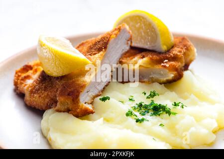 Hühnchen-Schnitzel mit Kartoffelpüree und Zitrone Stockfoto